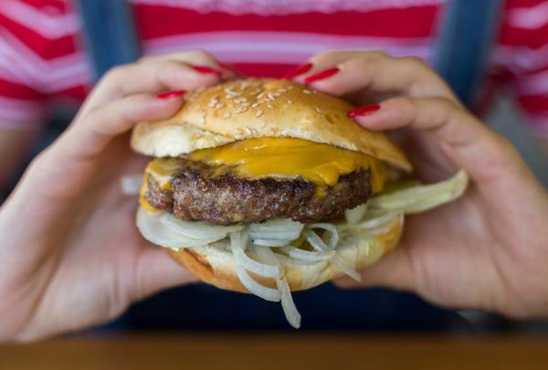 Woman eating a cheeseburger.